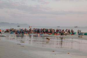 a crowd of people on a beach with a dog at Thiện Homestay Dốc Lết -Gần Biển & Nguyên Căn in Ba Ha