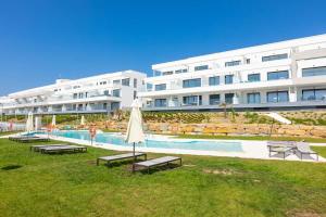 a large white building with a swimming pool and an umbrella at Doña Julia Sea Utopia in Casares