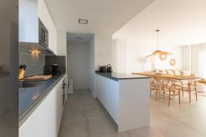 a kitchen with white cabinets and a dining table at Doña Julia Sea Utopia in Casares