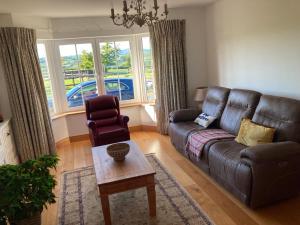 a living room with a leather couch and a chair at Hunthill in Tulach an Iarainn