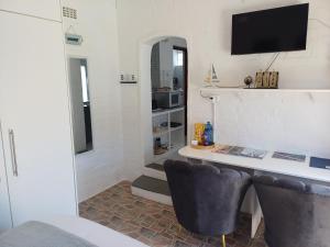 a room with a desk with a television and two chairs at Cozy Cove in Cape Town