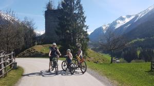three people on bikes on a road with a castle at B living Apartments in Neukirchen am Großvenediger