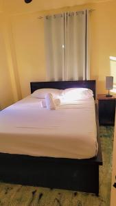 a bedroom with a large bed with white sheets at Comfortable and affordable in Saint Georgeʼs