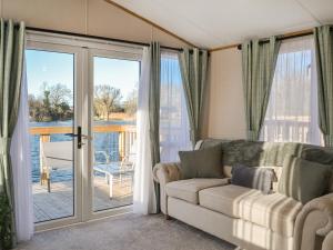 a living room with a couch and a sliding glass door at Waterfoot Lodge W09 in Amotherby