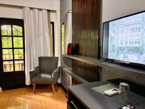 a living room with a television and a chair at Hotel Carmen in Puerto Iguazú