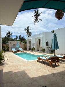 a pool with chairs and umbrellas next to a house at White Seeds Boutique Villas in Gili Trawangan