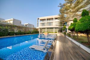 a swimming pool with lounge chairs in front of a building at VRR Astoria Hotel & Convention Center in Bangalore