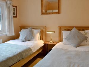 a bedroom with two beds and a mirror on the wall at Hawthorn in Llanddona