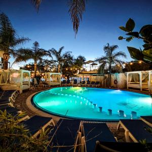 a swimming pool at night with tables and chairs at Resort Rocca di Vadaro - Seafront Suites, Rooms & Apartments in Capo Vaticano