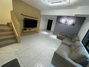a living room with a couch and a flat screen tv at Sweet Homestay Bahau in Bahau