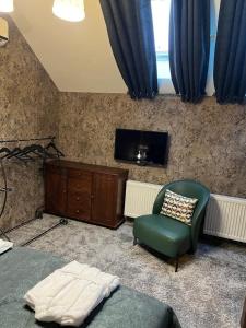 a bedroom with a bed and a chair and a tv at Шале Вершина in Palyanytsya