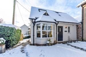 a small white house with snow on the roof at Finest Retreats - Cedar Tree Cottage in Clocaenog