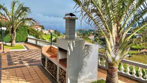 a outdoor oven on a balcony with a palm tree at The Gray House in Bicas