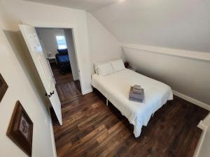 a small bedroom with a white bed and wooden floors at Getaway by the bay in Owen Sound