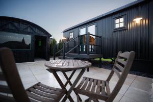 a small black tiny house with a table and two chairs at Friels Fairy Tree Lodges in Swatragh