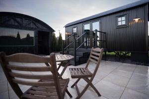 two chairs and a table on a patio with a tiny house at Friels Fairy Tree Lodges in Swatragh +10 photos