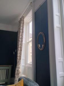 a room with a blue wall with a mirror and a window at The Gingernut in Ross on Wye