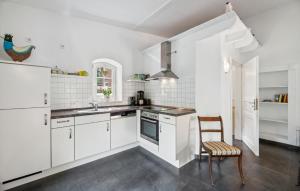 a kitchen with white cabinets and a sink and a chair at Beautiful Apartment In Wingst in Wingst