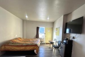 a bedroom with a bed and a table and a television at The Queen B Motel, Detroit-Warren in Warren