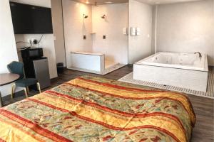a bedroom with a large bed and a bath tub at The Queen B Motel, Detroit-Warren in Warren