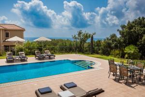 a swimming pool with chairs and a table next to a house at Athina Rose in Trapezaki