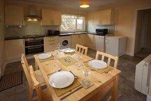 a kitchen with a wooden table with plates and wine glasses at Correay Cottage in Salen +2 photos