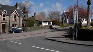 a street with two cars parked on the side of the road at Correay Cottage in Salen