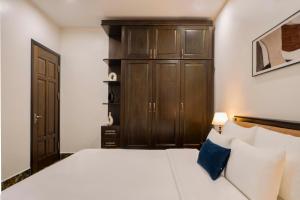 a bedroom with a white bed and wooden cabinets at Hai An Hotel Suites Ha Noi in Hanoi