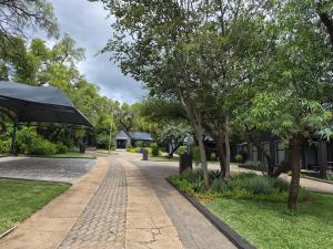 a cobblestone path in a park with trees and houses at Febe-Mari Guesthouse in Zeerust