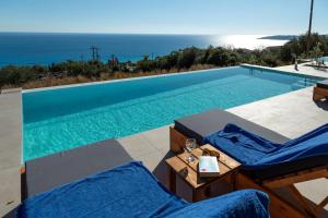 a swimming pool with two blue lounge chairs next to it at Ionian Dreaming in Lourdata