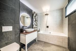 a bathroom with a sink and a tub and a mirror at Apartment Danton, Châtel - by EMERALD STAY in Châtel