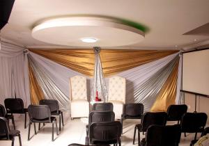 a room with a stage with chairs and a screen at Amazing Grace Inn BnB in East London