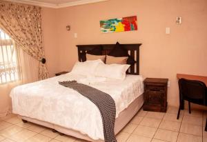 a bedroom with a bed with white sheets and a window at Amazing Grace Inn BnB in East London
