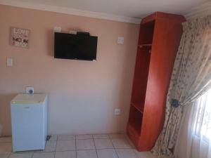 a room with a tv on the wall and a refrigerator at Amazing Grace Inn BnB in East London