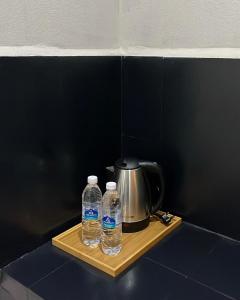 two bottles of water on a wooden tray next to a tea kettle at Temin Roomstay in Pulau Langkawi