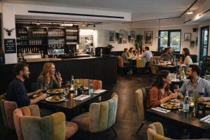 a group of people sitting at tables in a restaurant at Das Naturlich - Ruhiges Apartment Hotel nahe Regensburg in Sinzing