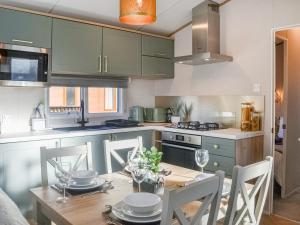 a kitchen with green cabinets and a wooden table with chairs at Waterfoot Lodge W09 in Amotherby
