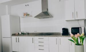 a kitchen with white cabinets and a vase of flowers at Living Sevilla & Parking gratis in Seville