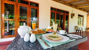 a table with a plate of food and a vase at Paddy Breeze Homestay in Sigiriya