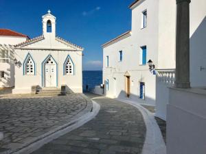 a church and a street in front of the ocean at The White House 1 in Andros