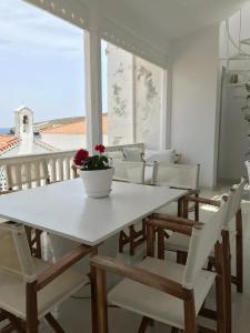 a white table and chairs with a vase on it at The White House 1 in Andros