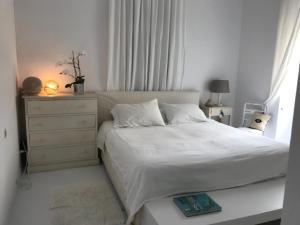 a bedroom with a white bed and a dresser and window at The White House 1 in Andros