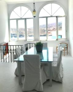 a table and chairs in a room with windows at The White House 1 in Andros +8 photos