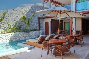 eine Terrasse mit Tischen, Stühlen und einem Sonnenschirm in der Unterkunft Villa Sol e Mar in Maragogi