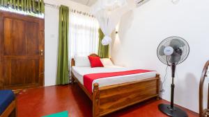 a bedroom with a bed with a fan and a window at Paddy Breeze Homestay in Sigiriya