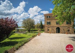a large stone building with a yard with benches at Villa Le Prata - Residenza del Vescovo in Montalcino