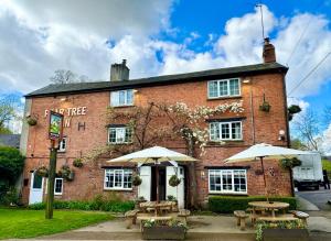 two tables and umbrellas in front of a brick building at The Pear Tree in Hook Norton