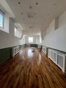 an empty room with a wooden floor and windows at The Cotswold Wellhouse in Tetbury