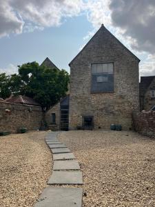 a stone house with a stone pathway in front of it at The Cotswold Wellhouse in Tetbury