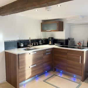 a kitchen with wooden cabinets and a sink at The Cotswold Wellhouse in Tetbury